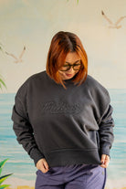 Person wearing a dark gray sweatshirt with 'Palmer' logo against a beach-themed wall.