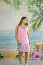 Woman wearing a pink dress with green trim against a tropical-themed backdrop