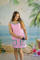 Woman wearing a pink dress with green trim against a tropical-themed backdrop