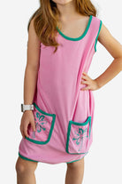 Pink dress with green trim worn by a person on a white background