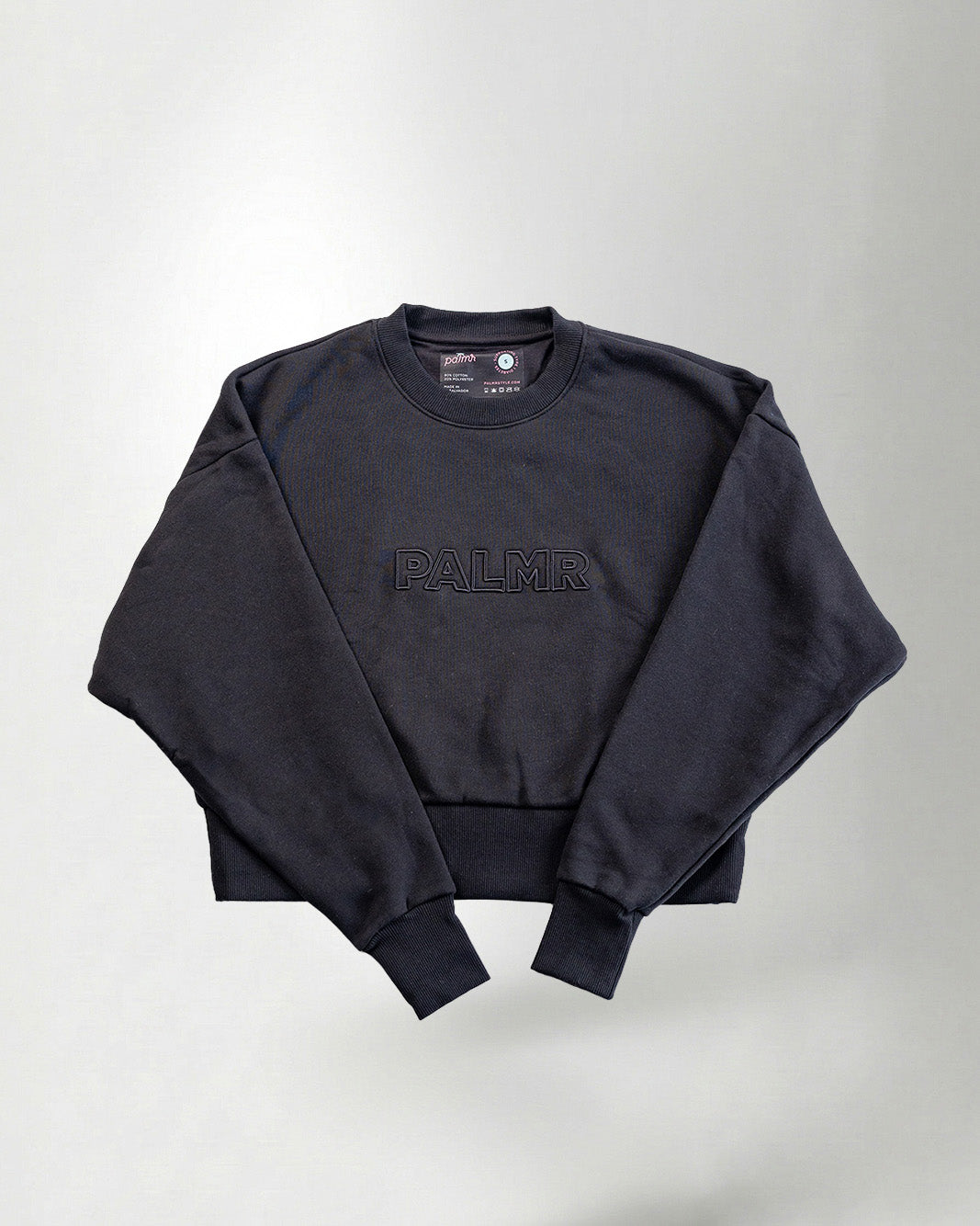 Sweatshirt with 'PALMR' branding, holding a floral-patterned bag against a white background.