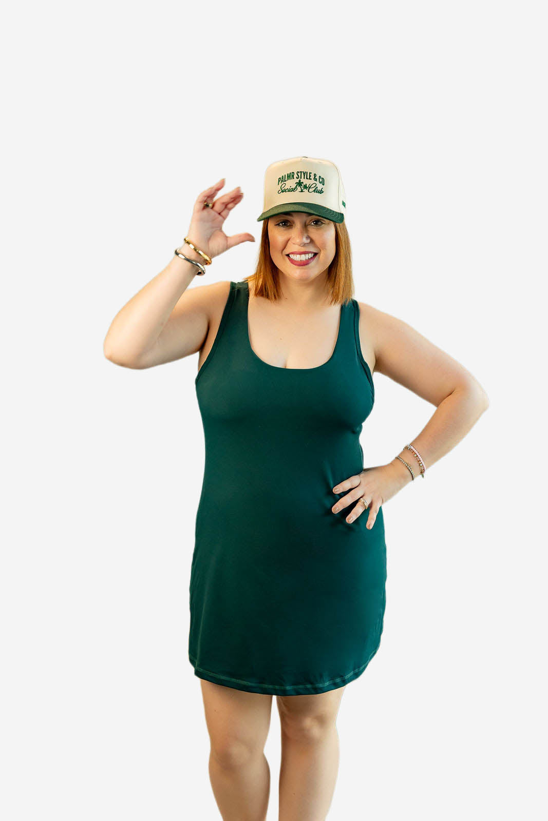Woman wearing a green tank dress and a cap on a white background