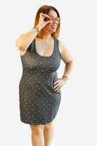 Woman wearing a dark gray tank dress with small white patterns on a plain background