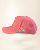 A pink perforated baseball cap with a green and white patterned trim along the brim and white 'Palmr' script embroidery on the side, shown against a plain cream background.