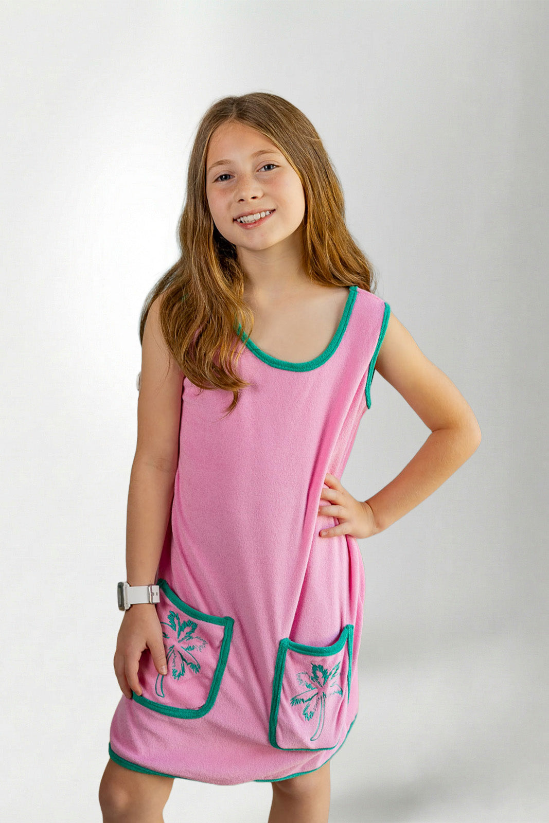 Young girl wearing a pink dress with green trim on a white background