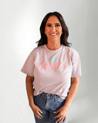 Person wearing a light pink t-shirt with 'Relax' printed on it against a plain background