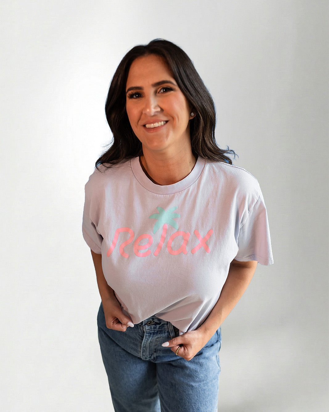 Person wearing a light pink t-shirt with 'Relax' printed on it against a plain background