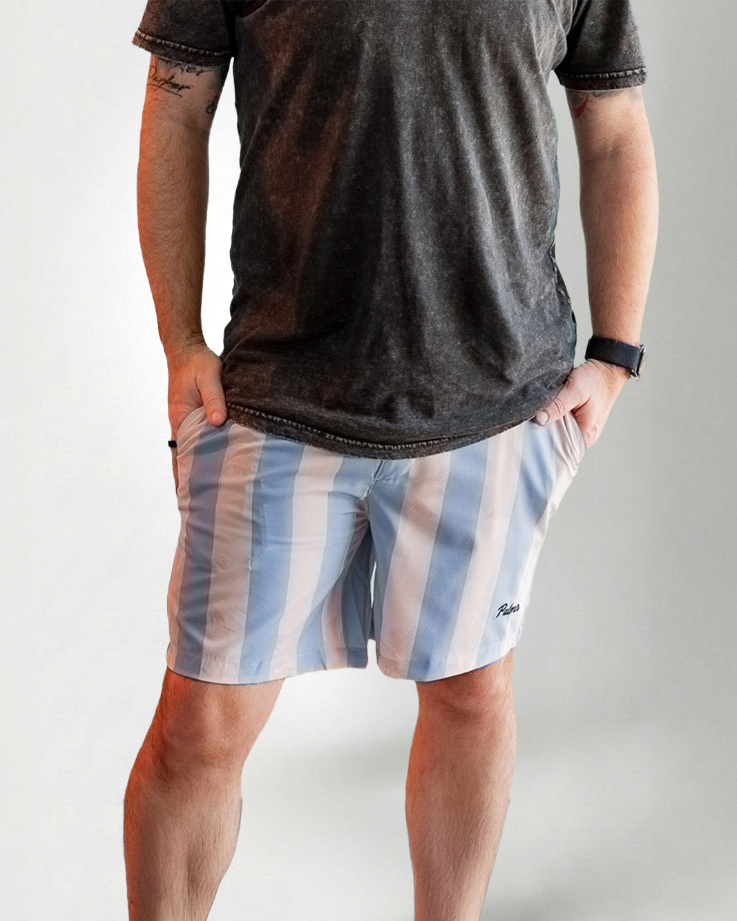 Man wearing Palmr Style Mens Ronnie Hybrid Swim Shorts Blue Tan Stripe Palm leaf Resort Wear and a black tee against a white background 