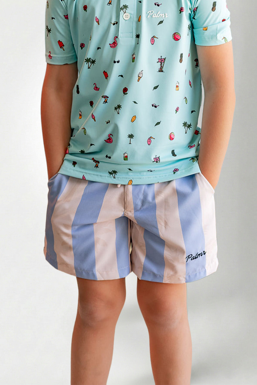 Person wearing a light blue patterned shirt and striped shorts on a plain background