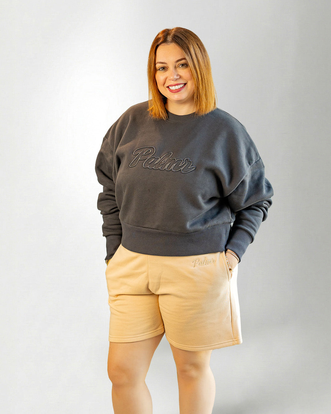 Woman wearing a  beige "Palmr" shorts over a gray background