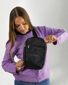 Girl using a "Touched by Type one purple cardigan" and a "Touched by type 1" Black crossbody bag against a gray background