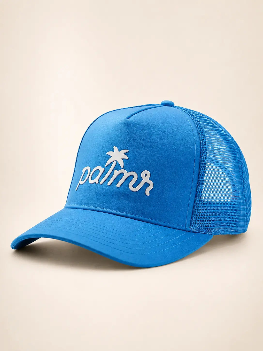A bright blue trucker cap with white embroidered 'palmr' script and a palm tree logo on the front, set against a plain beige background.