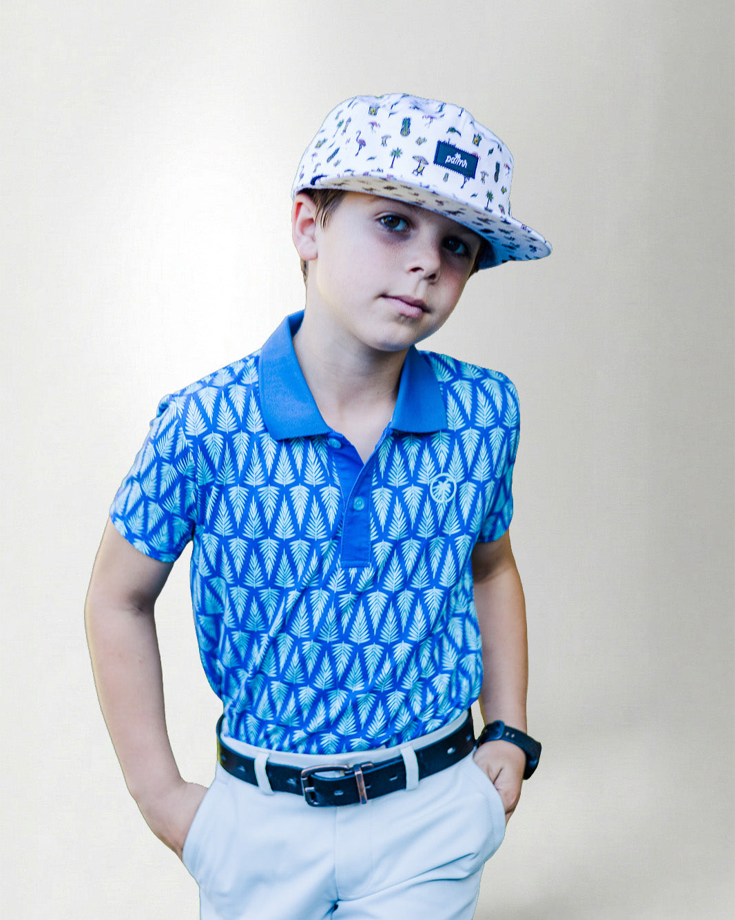 Child wearing a blue patterned polo shirt and cap with a white background