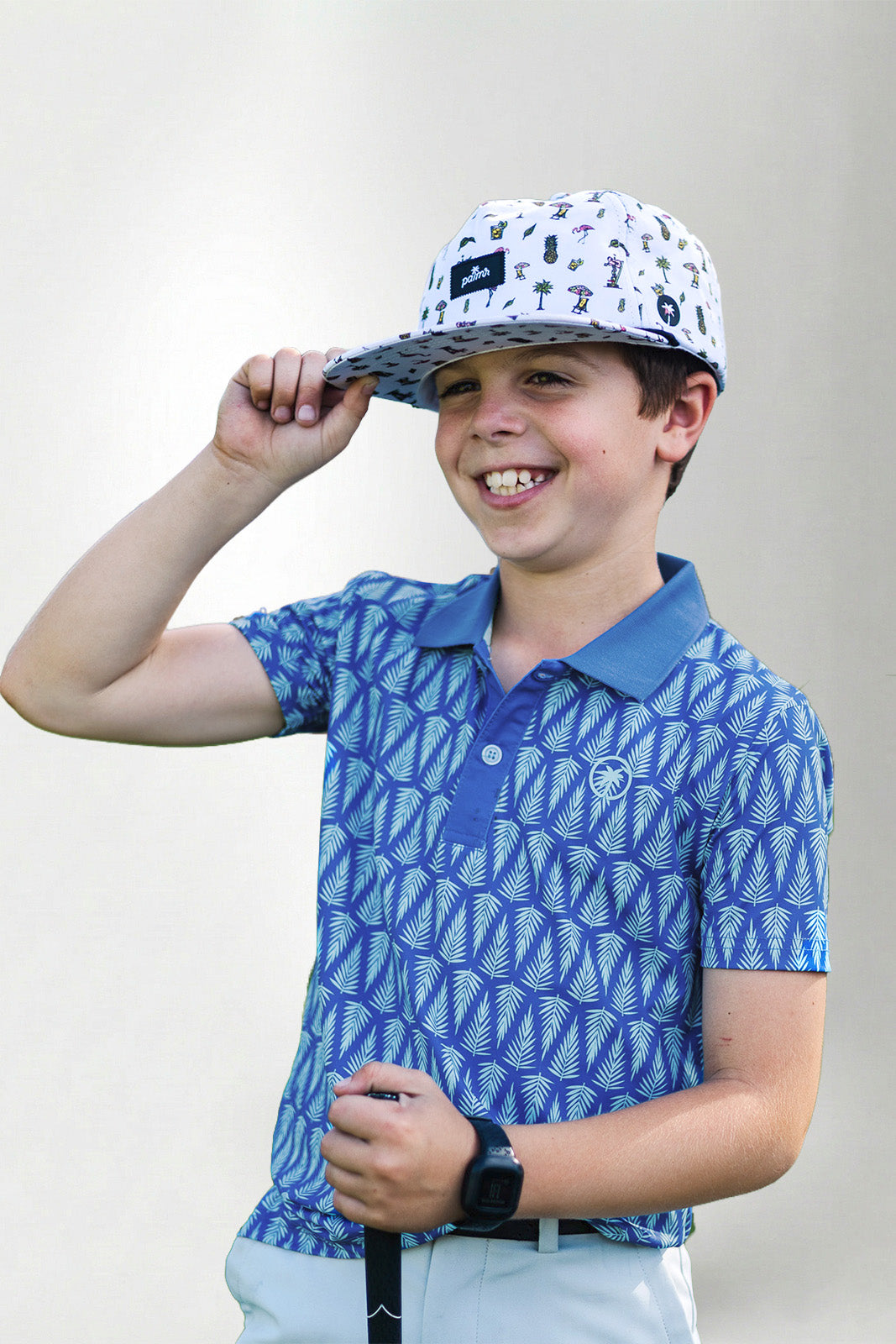 Child wearing a blue patterned polo shirt and cap with a white background