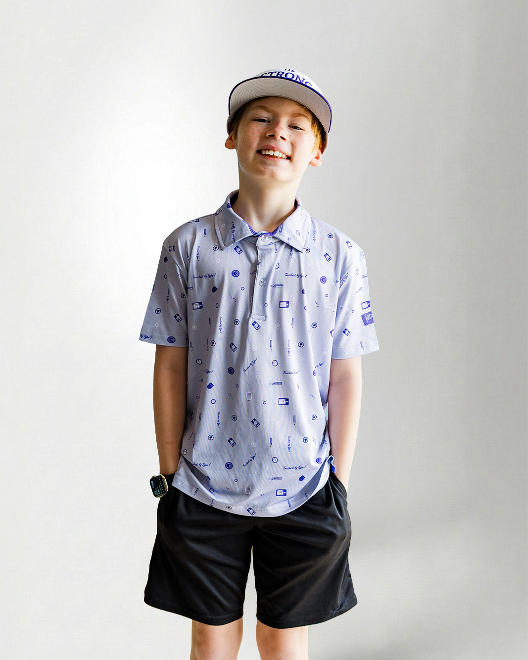 Child wearing a patterned polo shirt and cap on a plain background