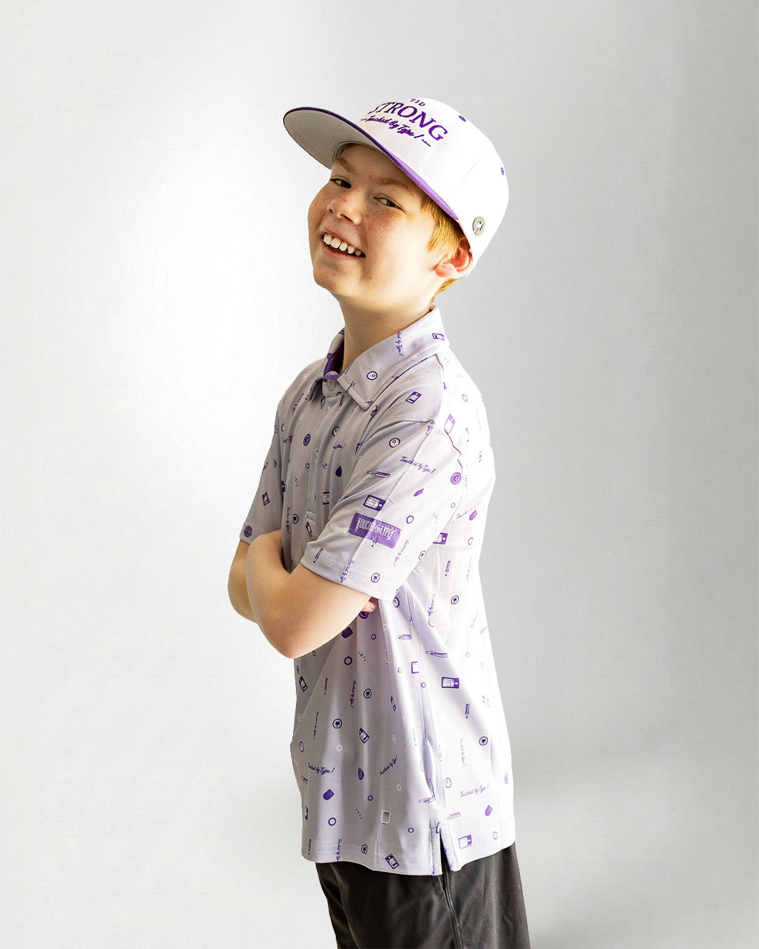 Child wearing a patterned polo shirt and cap on a plain background