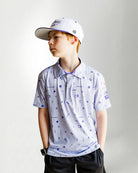 Child wearing a patterned polo shirt and cap on a plain background