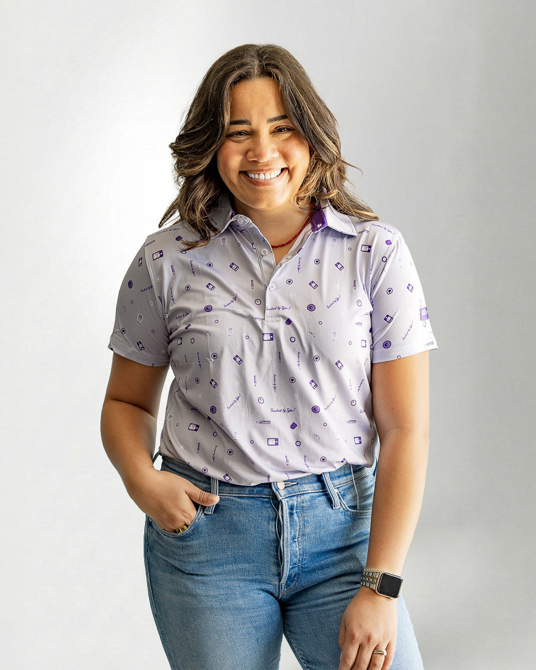 Woman wearing a patterned shirt and jeans against a plain background