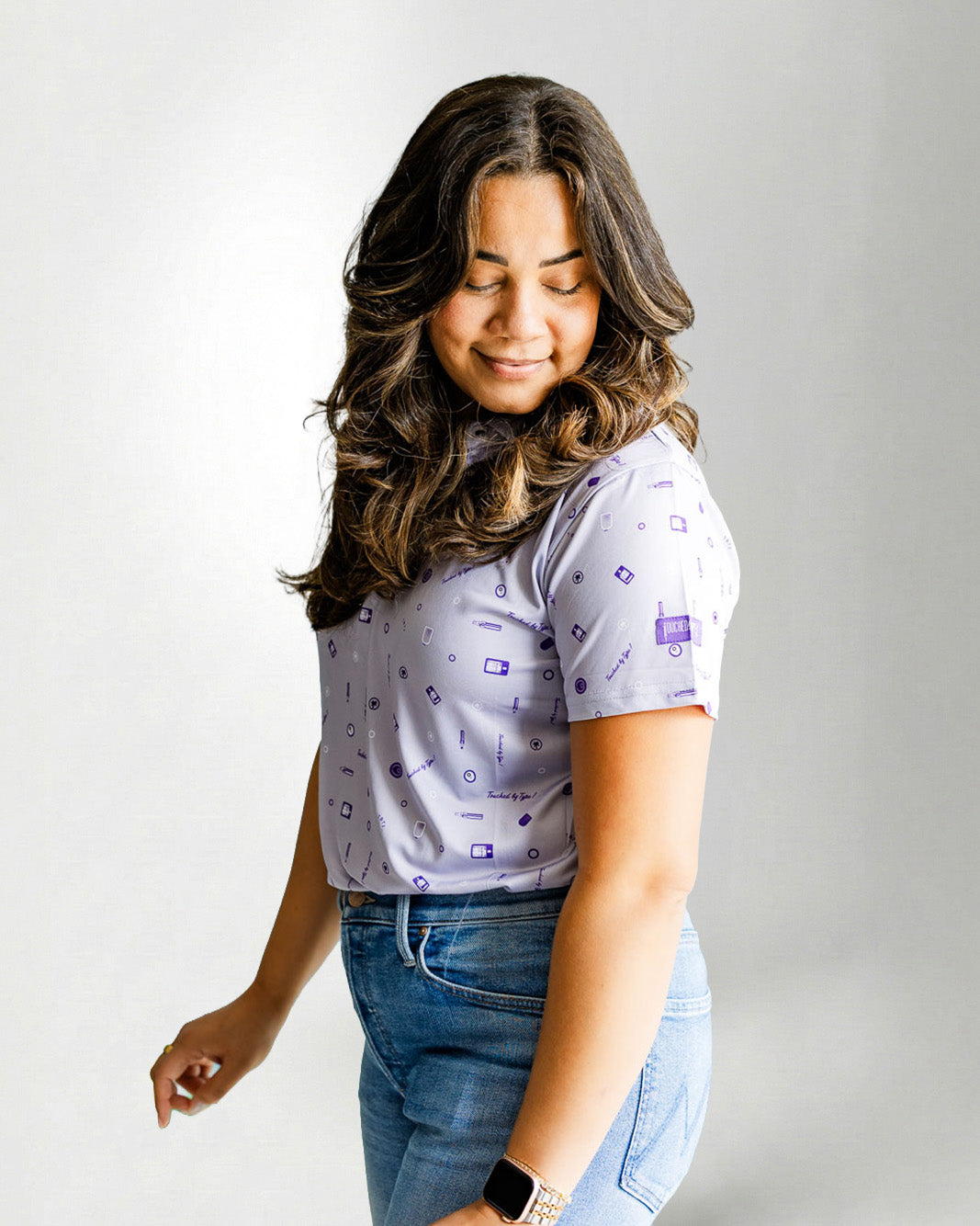 Woman wearing a patterned shirt and jeans against a plain background