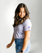 Woman wearing a patterned shirt and jeans against a plain background