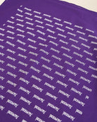 A close-up of a purple fabric surface printed repeatedly with the word 'Touched By Type 1' in white stylized lettering.