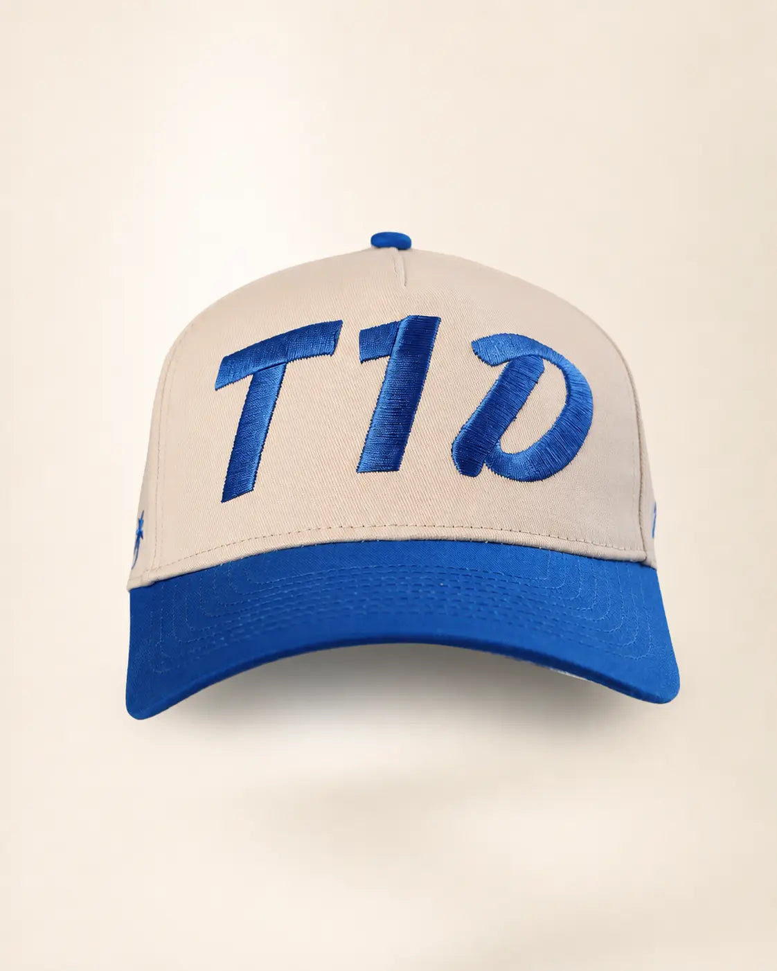 A structured baseball cap with a cream-colored front panel and brim, featuring a royal blue curved brim and matching blue embroidered lettering on the front.