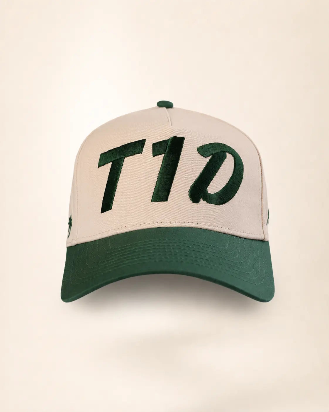 A baseball cap with a light beige crown and a dark green brim, featuring the letters 'T1D' embroidered in dark green across the front panels.