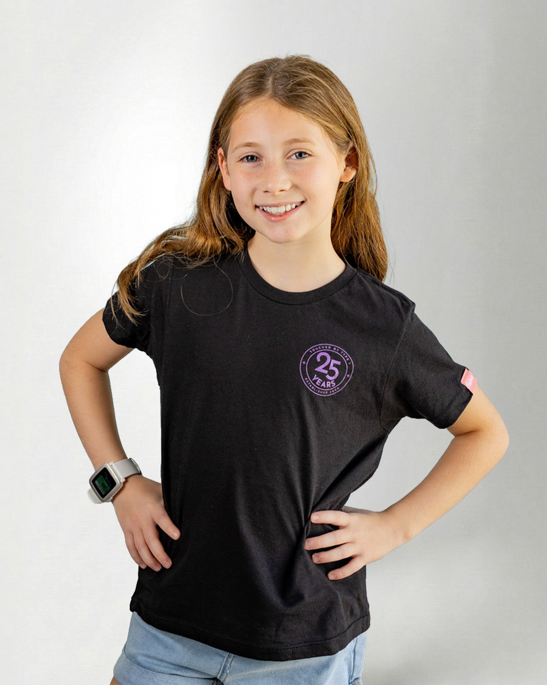 Girl wearing a black "touched by type 1" with purple diabetes related designs against a gray background.