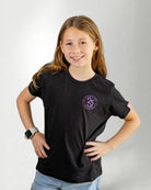 Girl wearing a black "touched by type 1" with purple diabetes related designs against a gray background.