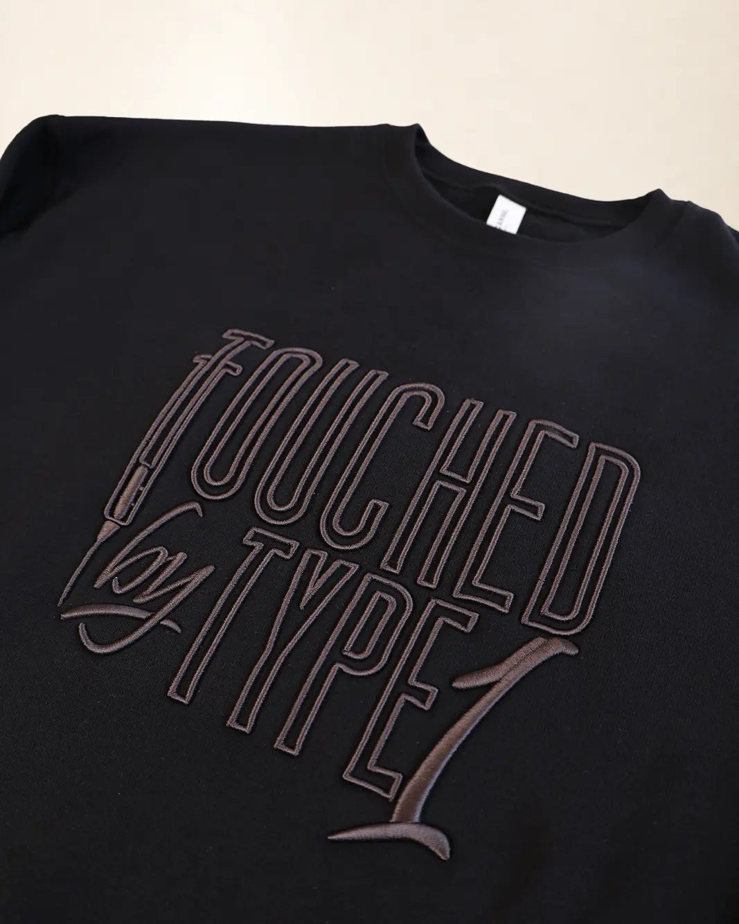 Black sweatshirt with 3d stylized embroidery lettering that says 'Touched By Type 1'