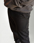 Person wearing a dark gray hoodie and pants with white sneakers on a light gray background