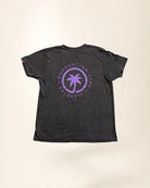 Black t-shirt with purple palm tree design and text on a beige background