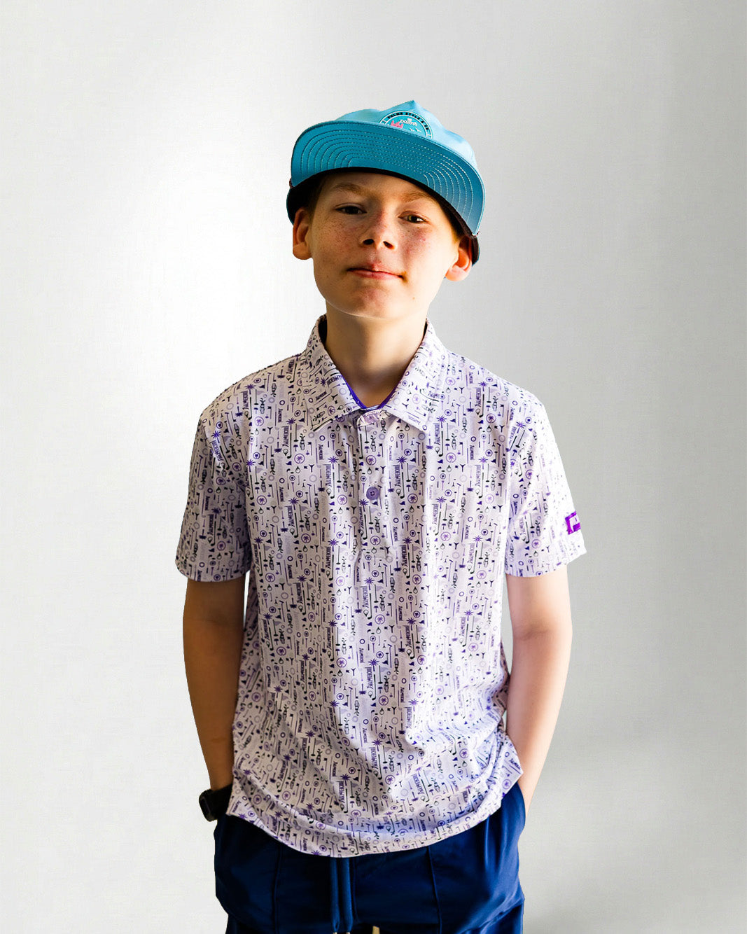Child wearing a patterned shirt and blue cap against a plain background
