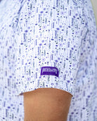Man wearing a patterned shirt and cap against a plain background