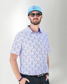 Man wearing a patterned shirt and cap against a plain background