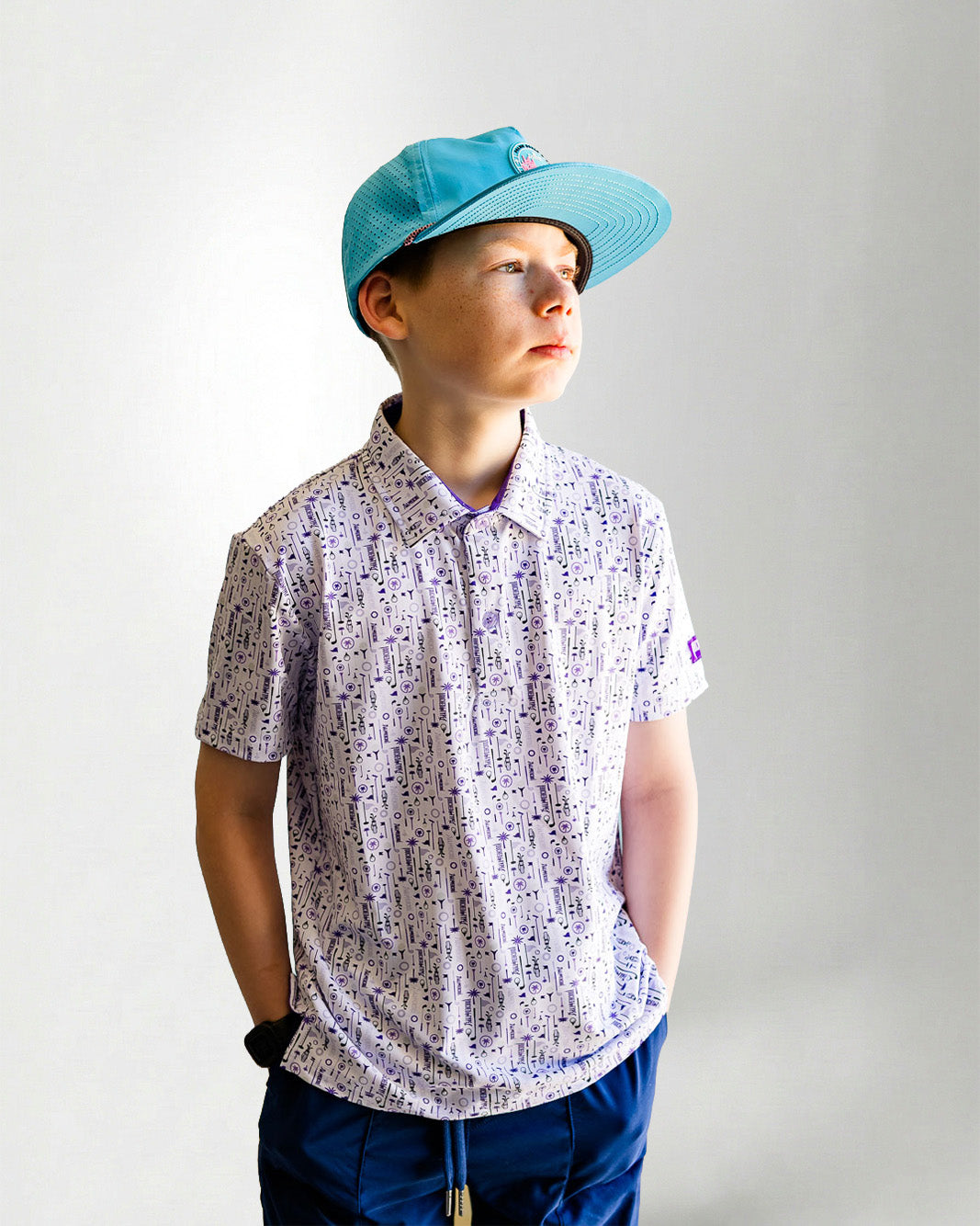 Child wearing a patterned shirt and blue cap against a plain background