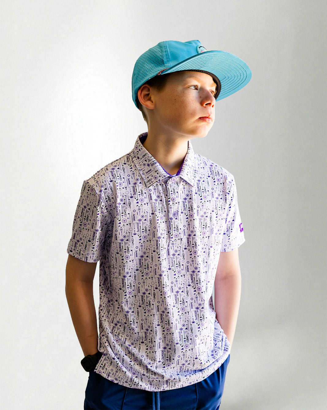 Child wearing a patterned shirt and blue cap against a plain background