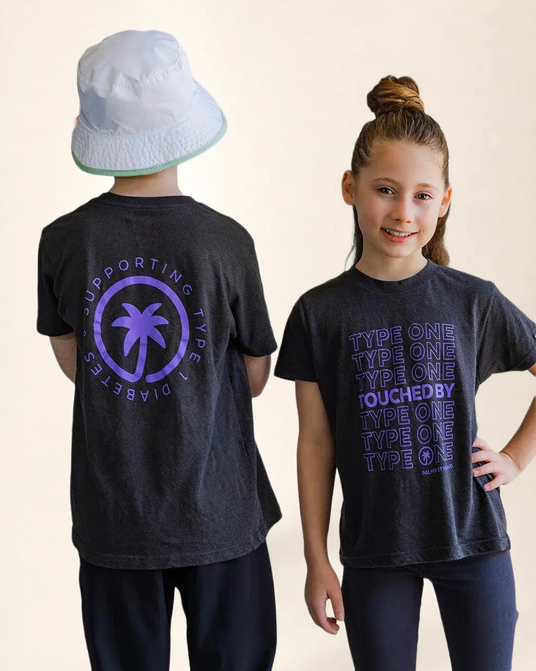 Two children wearing black t-shirts with purple text and a palm tree design on a plain background