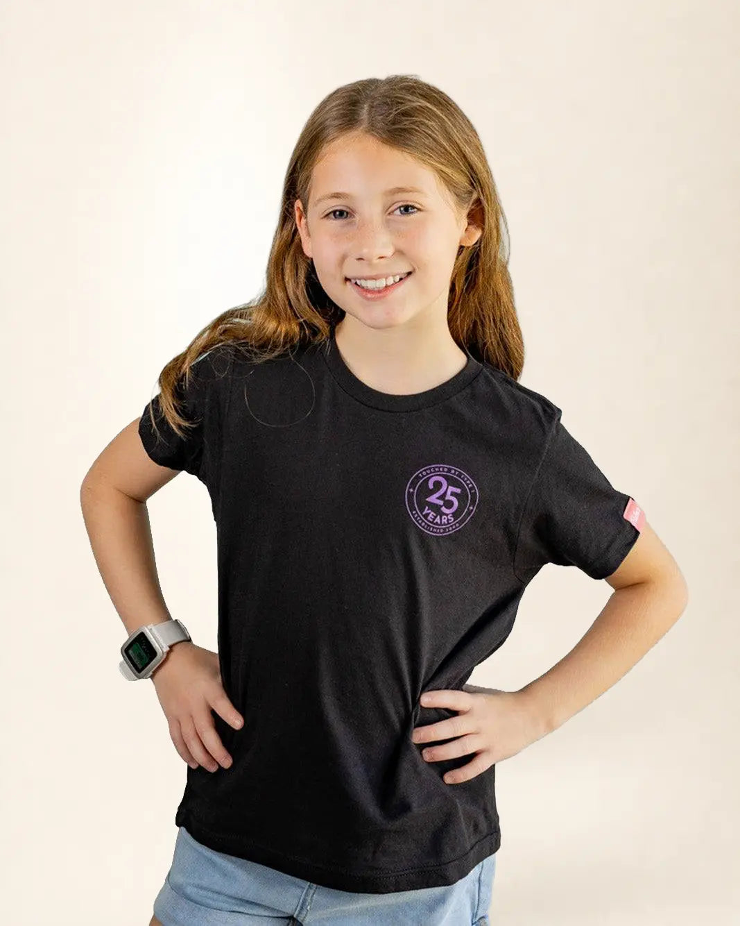 Young girl wearing a black t-shirt with a logo on a beige background