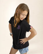 Young girl wearing a black t-shirt with a logo on a beige background