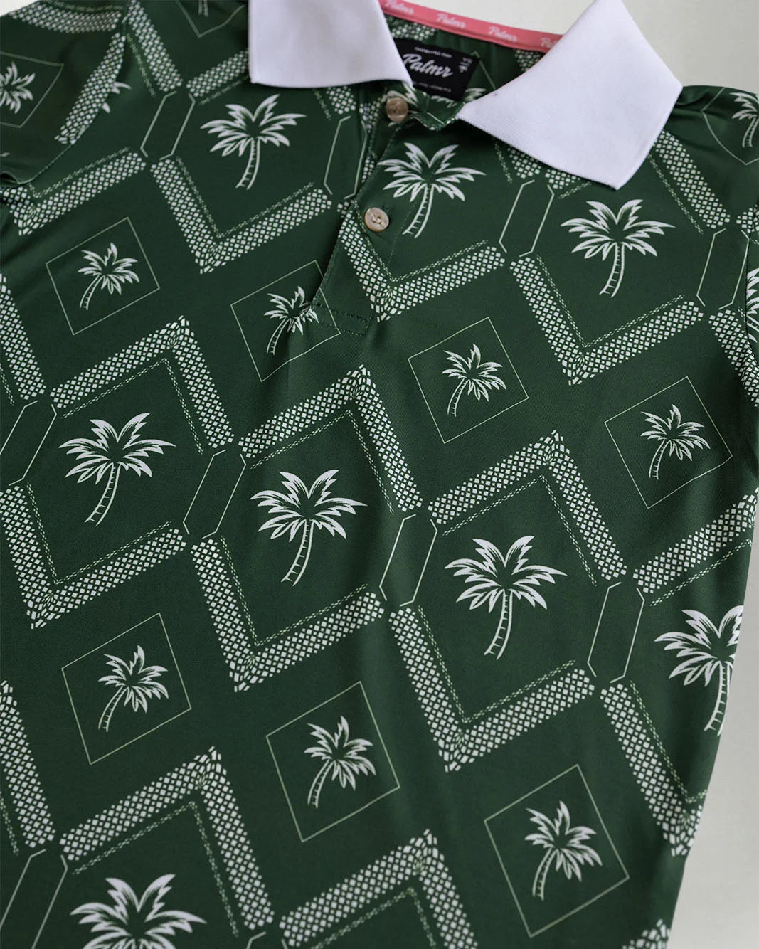 Green polo shirt with contrasting white neck showcasing a palm pattern against a grey background