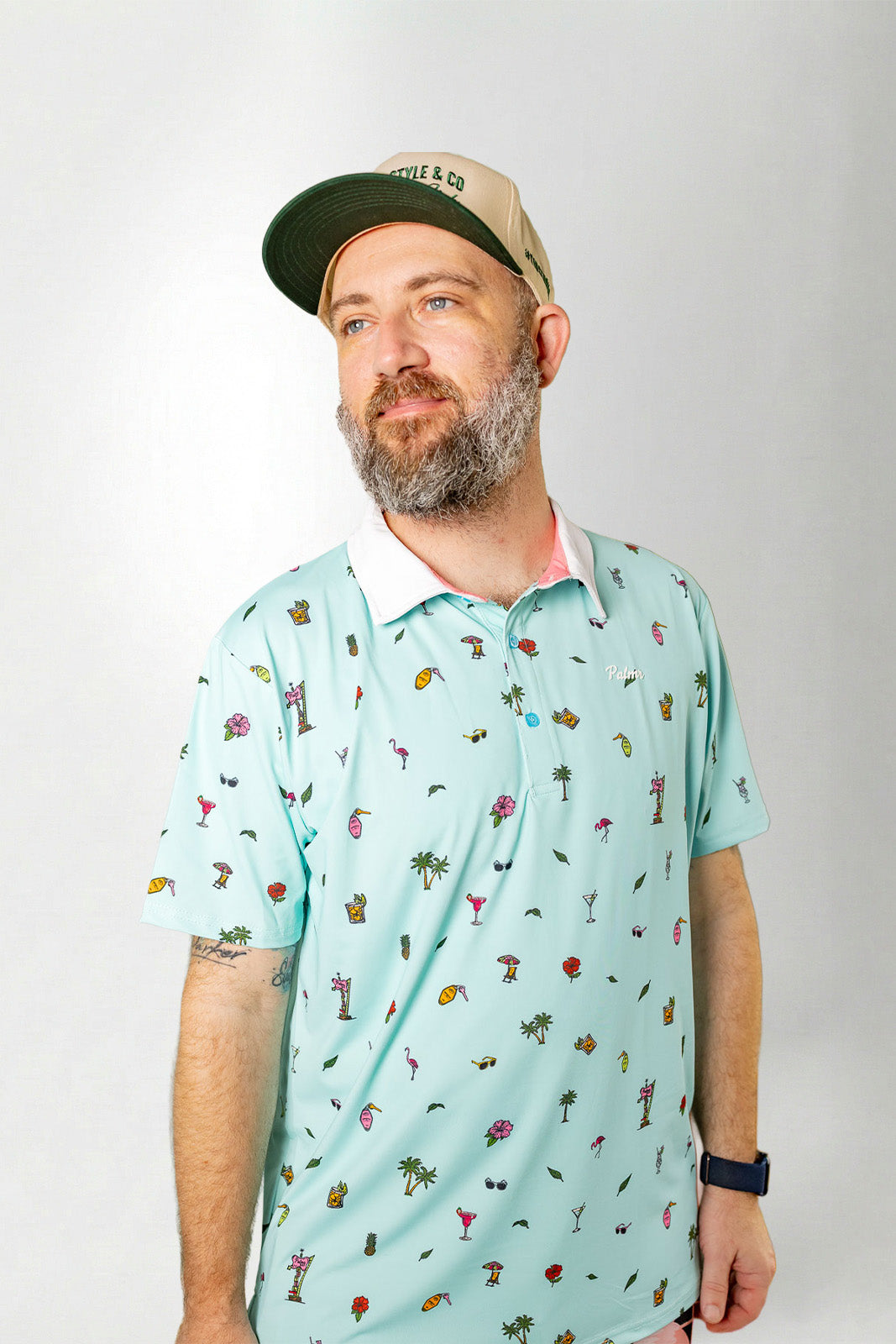 Man wearing a light blue polo shirt with a pattern and a cap on a white background