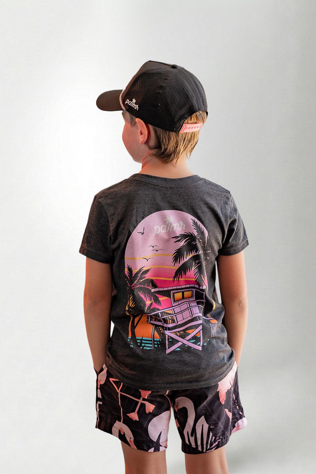 Child wearing a black t-shirt with a colorful graphic design on the back, standing against a plain background.