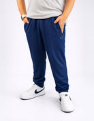 Person wearing navy blue jogger pants and white sneakers on a white background