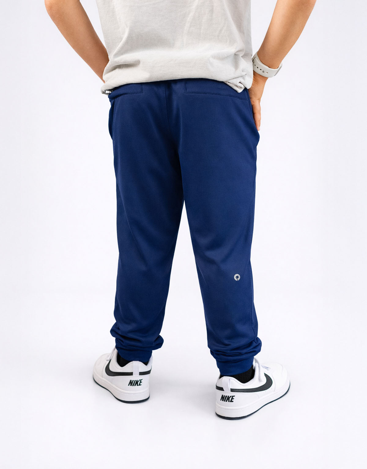 Person wearing blue pants and white sneakers on a white background