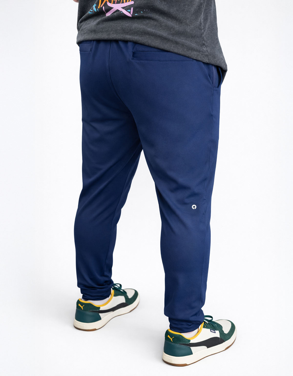 Person wearing navy blue jogger pants with a white background