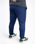 Person wearing navy blue jogger pants with a white background