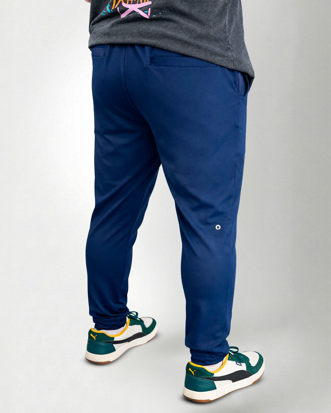 Person wearing blue pants and green sneakers on a white background