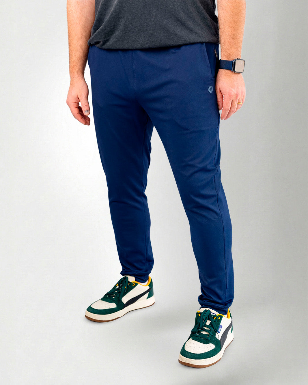 Person wearing blue pants and green sneakers on a white background