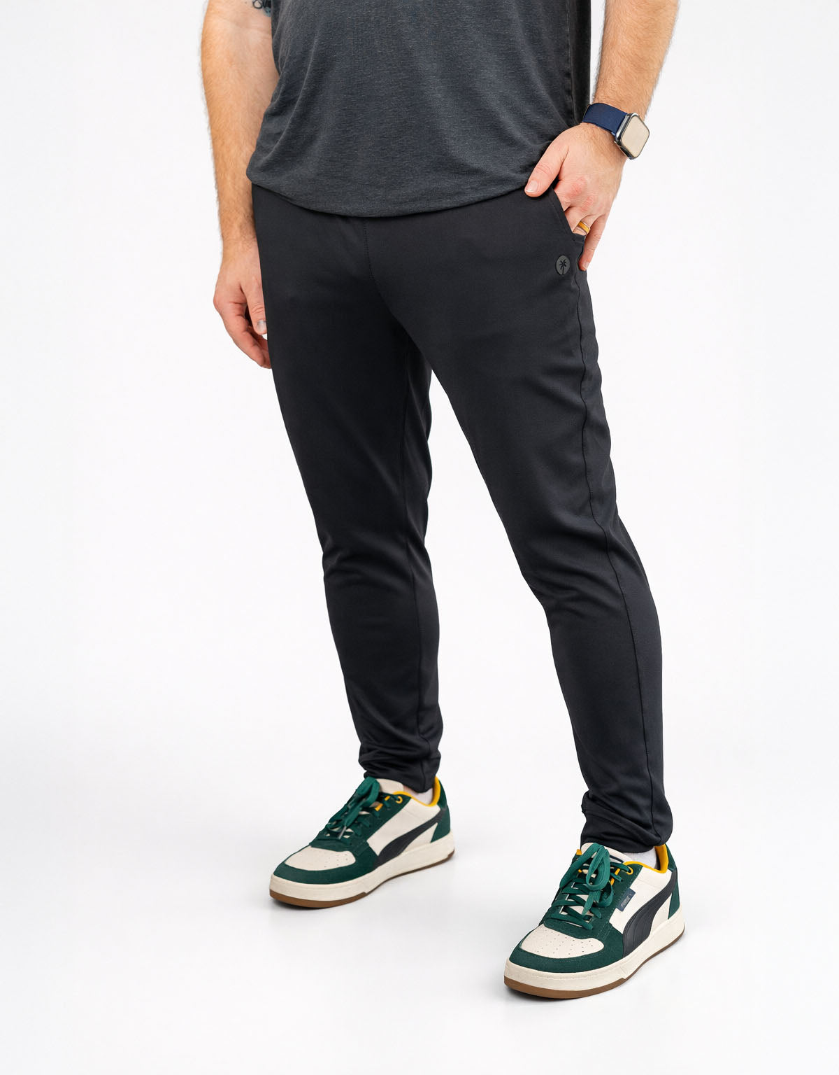Person wearing black pants and green sneakers on a white background